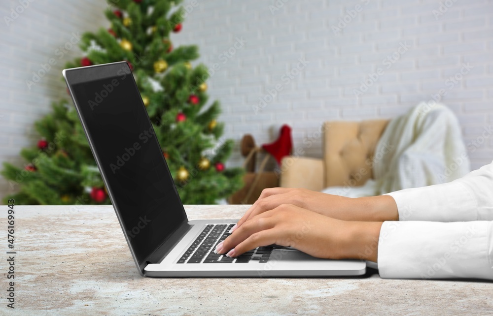 Naklejka premium Young woman work on laptop computer with blank display screen with living room interior design decorated for Christmas,