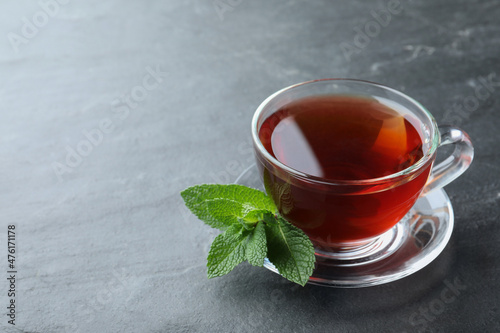 Cup of hot aromatic tea with mint on grey table. Space for text