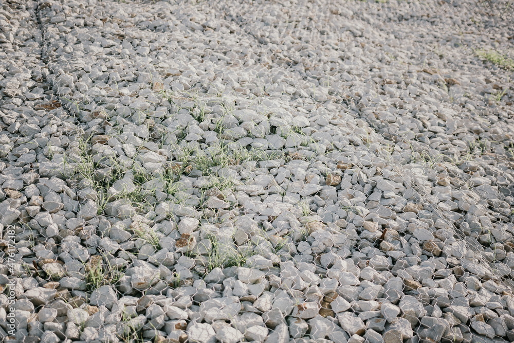 Granite stones behind a metal grate for strengthening the slope. Stones behind the wire. grey texture. construction. Granite stones behind a metal grate for strengthening the slope. Stones behind the wire. grey texture. construction.