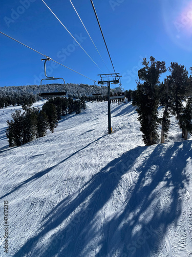 View of chairlift and snow covered slopes at a ski resort on a bluebird winter day in Tahoe