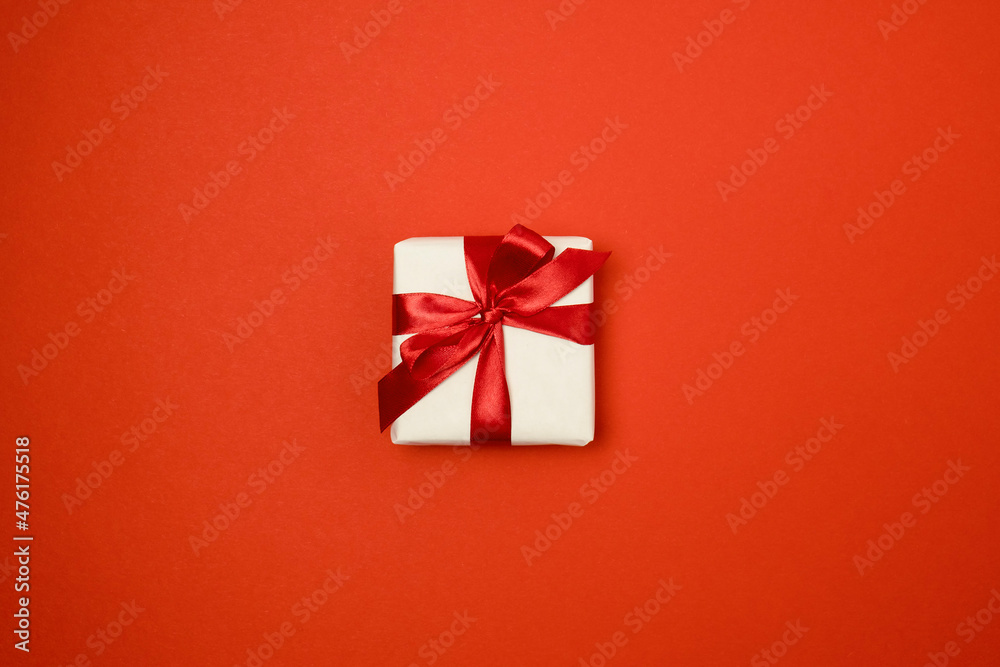Gift box with red ribbon bow on red background. Top view