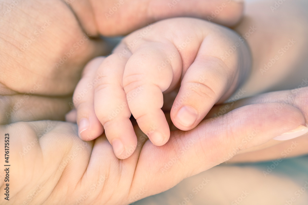 Mother holds newborn baby hand. Care concept. Toned photo Mother holds newborn baby hand. Care concept. Toned photo