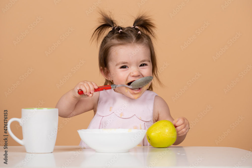 Kid eat healthy nutrition, baby food. Babies eating with spoon. Babys first meal. The child eats on his own with a spoon and plate. Kid eat healthy nutrition, baby food. Babies eating with spoon. Babys first meal. The child eats on his own with a spoon and plate.