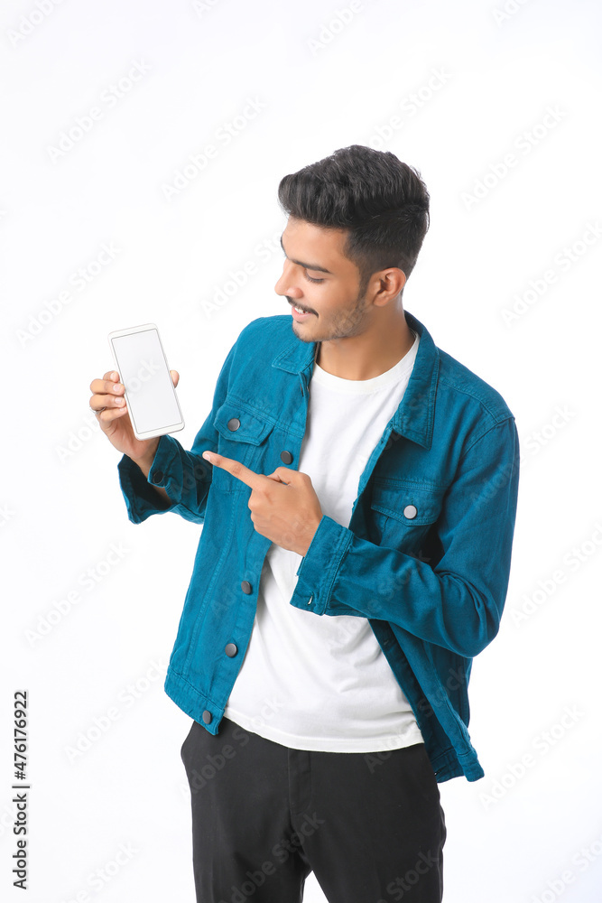 Young indian man showing smartphone screen on white background. Young indian man showing smartphone screen on white background.