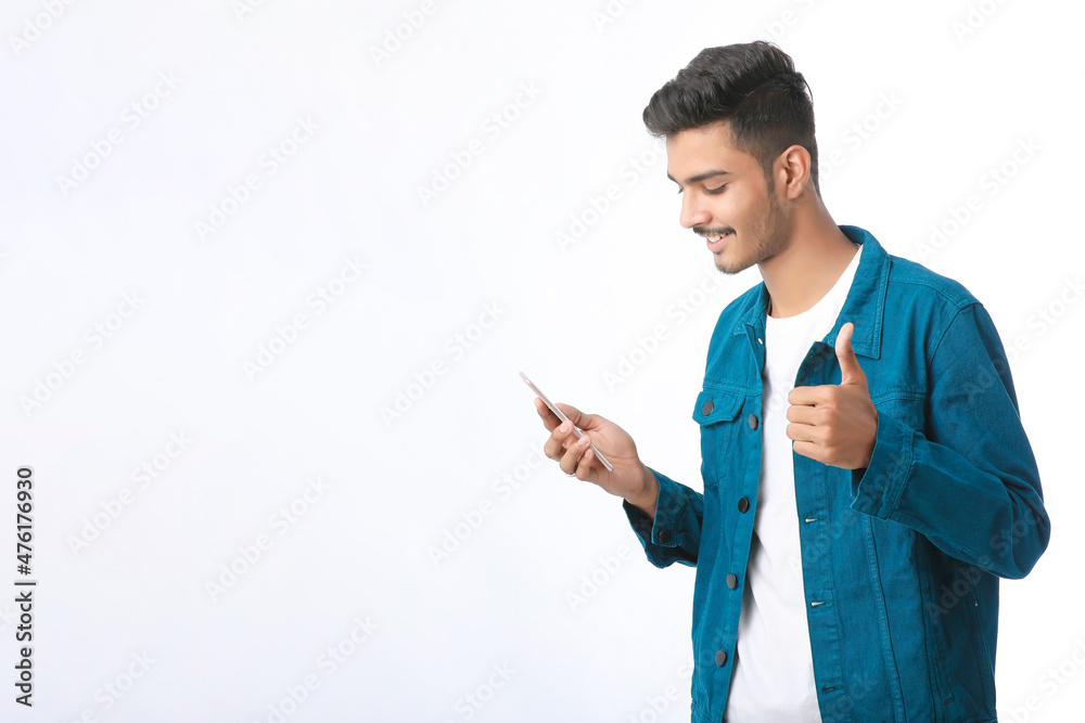 Young indian man using smartphone and giving expression on white background. Young indian man using smartphone and giving expression on white background.