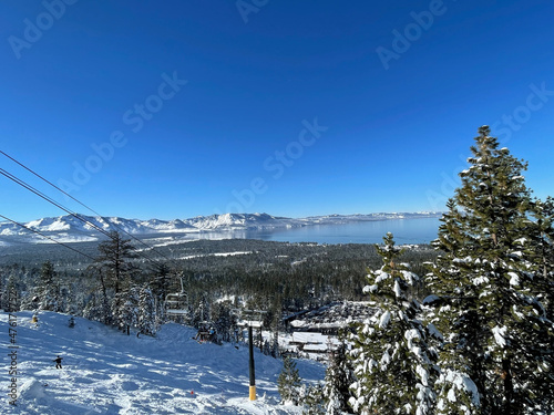 Scenic view of Lake Tahoe framed by snow covered trees, as seen from a ski resort on a bluebird winter day