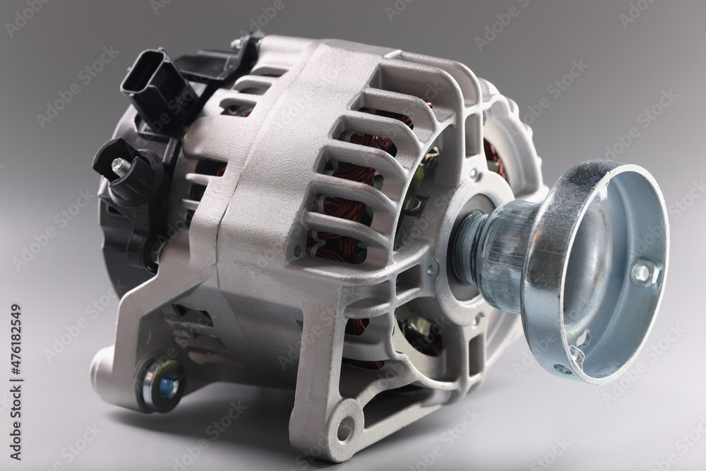 Metal motor with wire and plugs lies on grey surface, production of complex equipment Metal motor with wire and plugs lies on grey surface, production of complex equipment