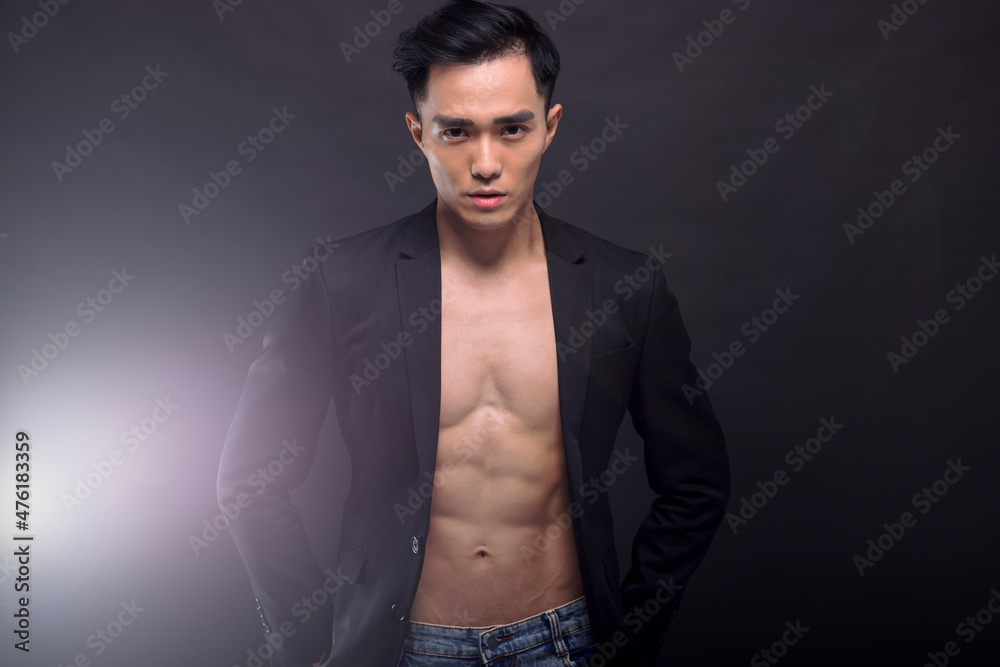 Strong, fit and handsome asian young  man over black background