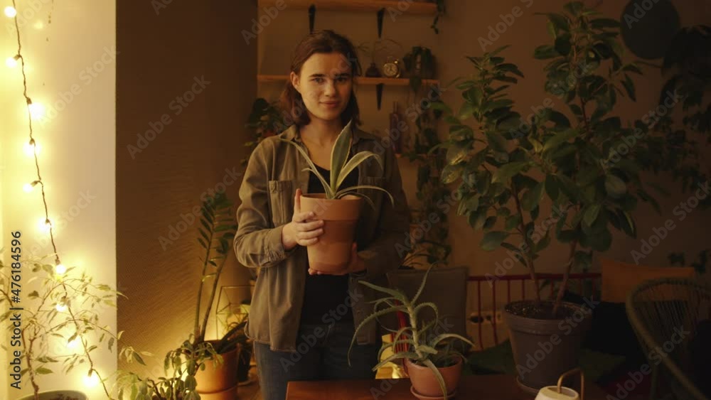 custom made wallpaper toronto digitalA happy young girl stands in the middle her home greenhouse and holding a clay pot with a houseplant in her hands. Slow motion