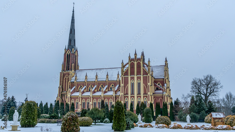 Neo-Gothic cathedral church in the town of Gervyaty in Belarus in the winter on dramatic sky background. Space for text.