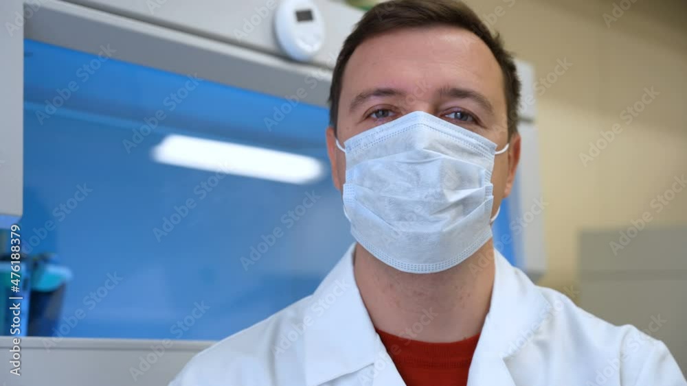 Chemistry lab researcher man in mask talking look camera biomedical laboratory.Scientist standing in vintage style laboratory and giving speech. Happy scientist in room with laboratory box in UV light Chemistry lab researcher man in mask talking look camera biomedical laboratory.Scientist standing in vintage style laboratory and giving speech. Happy scientist in room with laboratory box in UV light