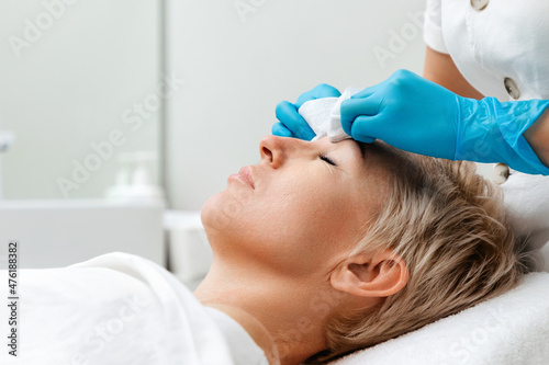Professional care in beauty salon. Cosmetologist does a deep mechanical cleaning of the client's face. Side view. Acne concept