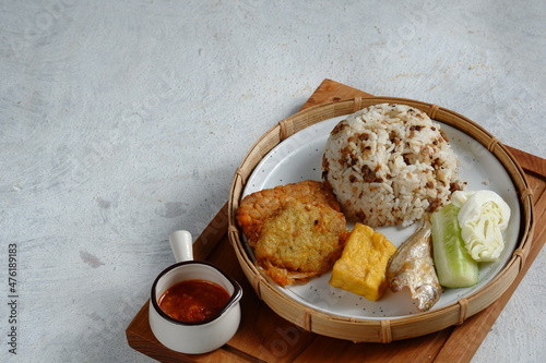 Nasi Tutug Oncom. Traditional Sundanese meal of rice mixed with fermented soybean; accompanied with grilled prawn, tempeh, tofu, salted fish, vegetables and chili paste photo