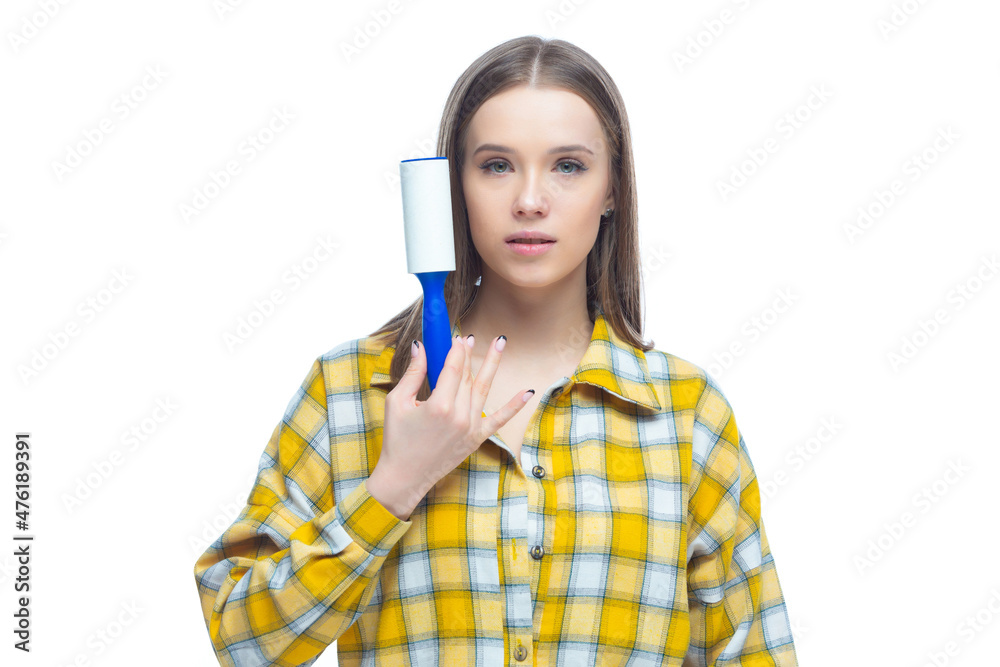 Portrait of young woman using a lint remover to clean yellow checkered shirt from dust, hair, lint and fluff, isolated on white background