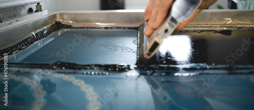 Quadro em tela Close up of artisan applying ink on stencils on screen printing machine in works