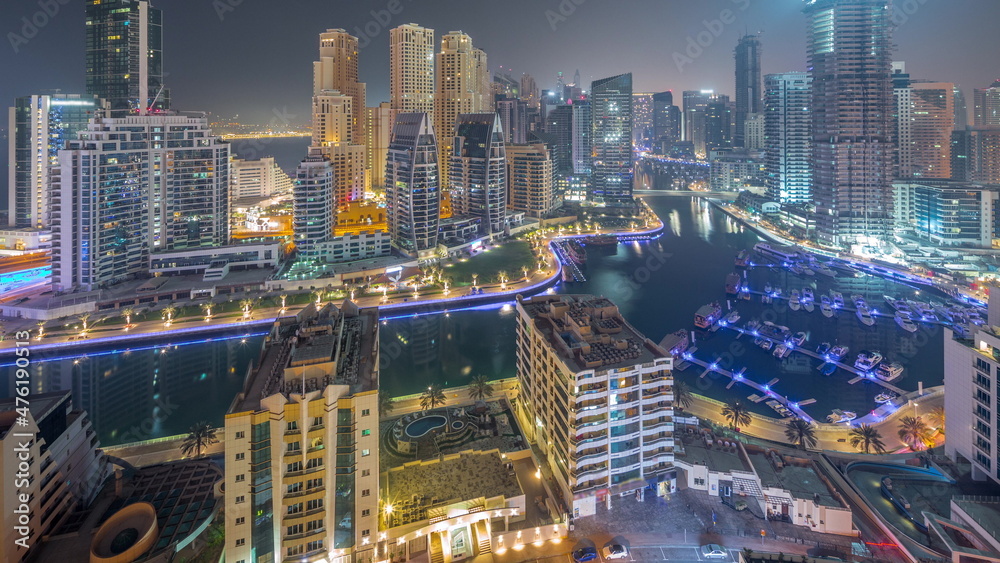 Fototapeta premium Dubai Marina with several boats and yachts parked in harbor and skyscrapers around canal aerial night to day timelapse.
