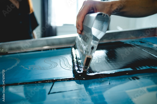 Cropped shot of craftsman applying plastisol ink on screen printing machine  photo