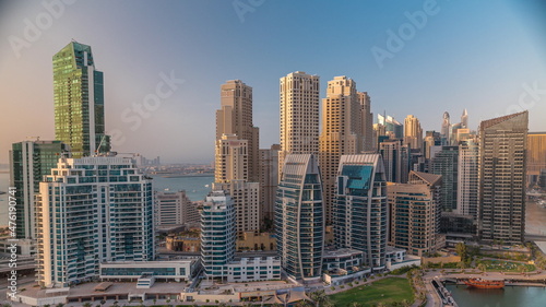 Dubai Marina with several boat and yachts parked in harbor and skyscrapers around canal aerial timelapse.