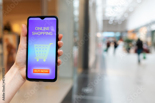 A female's hand shows a smartphone with a promo code for a discount on a purchase in an online store. Blurred background. The concept of ecommerce