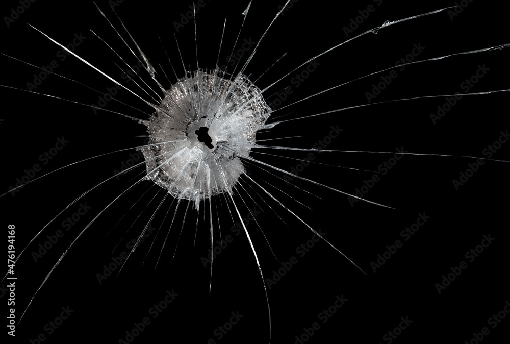 Obraz premium a crack on a broken glass mirror on a black background lines fragments bullet hole