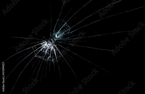 a crack on a broken glass mirror on a black background lines fragments bullet hole