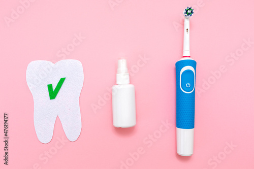 An electric toothbrush, a mouth freshener and a felt-cut tooth. Flat lay. Pink background. Oral hygiene cavity concept