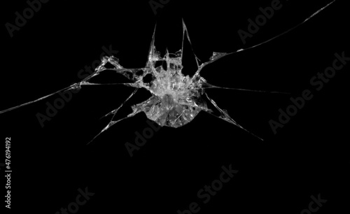 a crack on a broken glass mirror on a black background lines fragments bullet hole