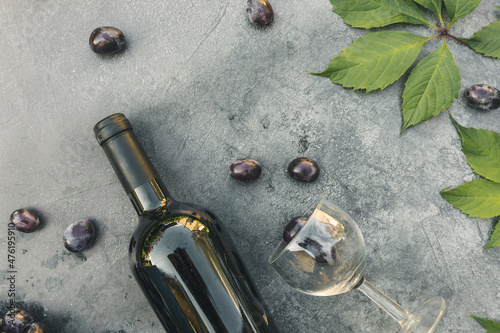 Bottle of red wine, green vine, wineglass and ripe grape on vintage dark stone table background. Top view copy space for text. Wine shop wine bar winery or wine tasting concept