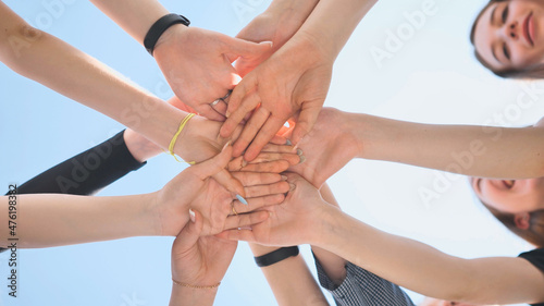 Cheerful girls join hands together as a sign of unity and joint successful work. Teamwork stacking hand concept.