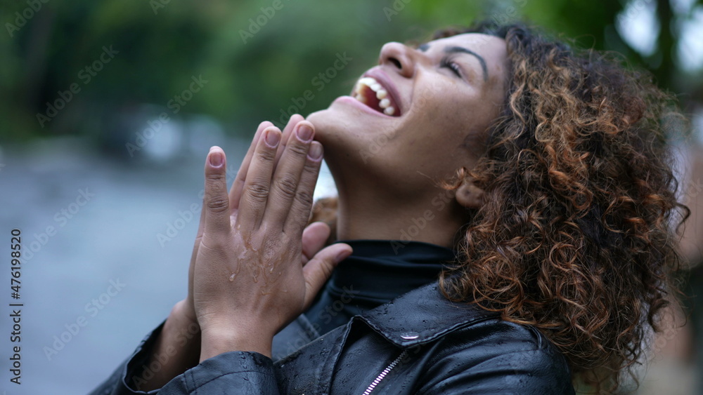 Young black woman standing in the rain looking at sky with HOPE and FAITH. person feels rain eyes closed