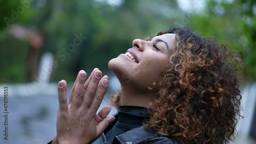 Young black woman standing in the rain looking at sky with HOPE and FAITH. person feels rain eyes closed © Marco