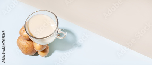 Alternative plant milk. Modern composition with a cup with potato milk that balances on a pile of potatoes