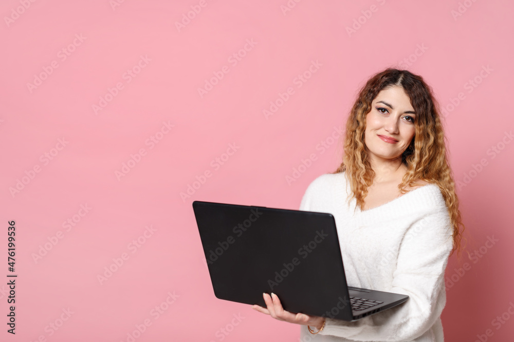 Woman standing isolated on a pink background using a laptop computer. Woman standing isolated on a pink background using a laptop computer.