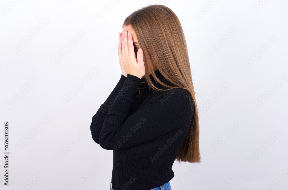 Sad Young caucasian girl wearing black turtleneck over white background covering face with hands and crying. Sad Young caucasian girl wearing black turtleneck over white background covering face with hands and crying.