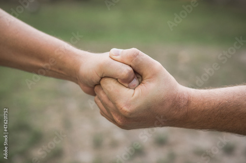 Two hands, isolated arm, helping hand of a friend. Handshake, arms. Friendly handshake, friends greeting. Rescue, helping hand. Male hand united in handshake. Man help hands, guardianship, protection © Maria