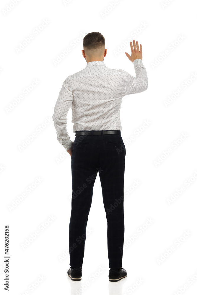 Man in pantsuit and white shirt is standing with hand raised. Rear view. Isolated. Man in pantsuit and white shirt is standing with hand raised. Rear view. Isolated.