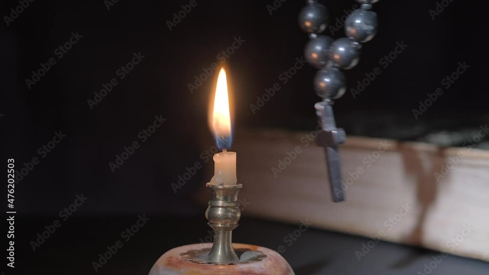 Close-up of burning candle and swinging rosary Close-up of burning candle and swinging rosary