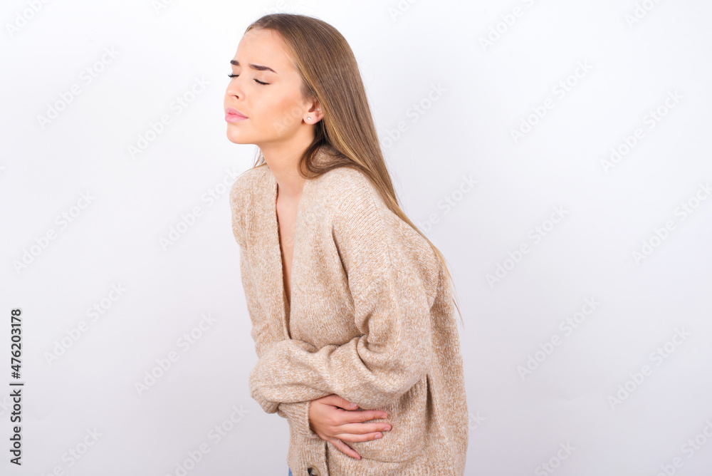 young caucasian girl wearing knitted sweater over white background got stomachache young caucasian girl wearing knitted sweater over white background got stomachache