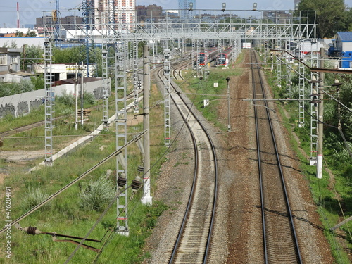 suburban railway tracks with poles and rails in summer