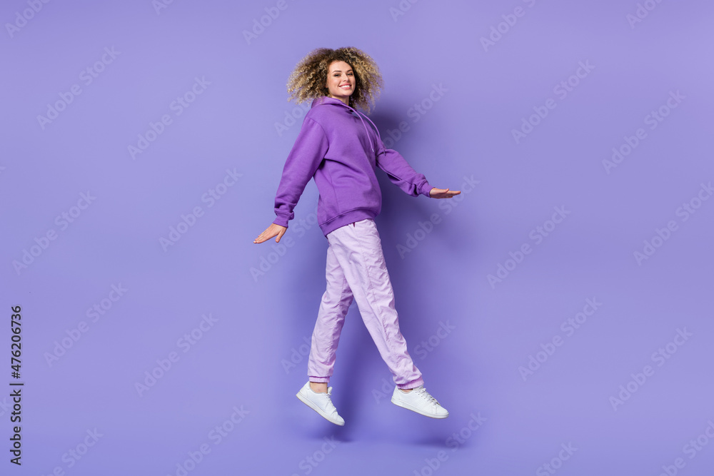 Photo of sweet excited woman wear sweatshirt jumping high walking isolated violet color background