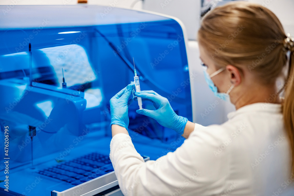 Discovery of an efficient vaccine. Rear view of a scientist standing in a lab and holding a syringe with a new vaccine. Discovery of an efficient vaccine. Rear view of a scientist standing in a lab and holding a syringe with a new vaccine.