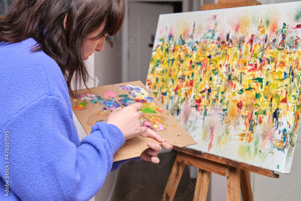 Young woman painting on canvas with oil paints at home. Young woman painting on canvas with oil paints at home.