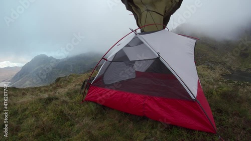 A person erecting a wild camping tent in strong mountain winds
