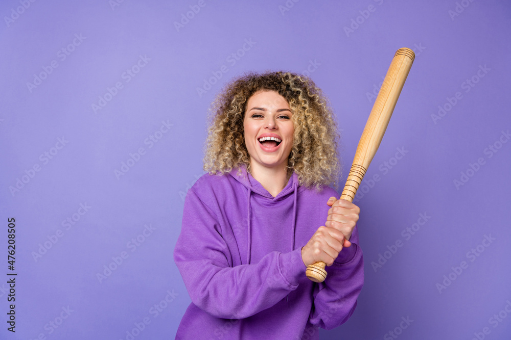 Photo of funky excited lady dressed hoodie laughing holding baseball beat isolated purple color background Photo of funky excited lady dressed hoodie laughing holding baseball beat isolated purple color background