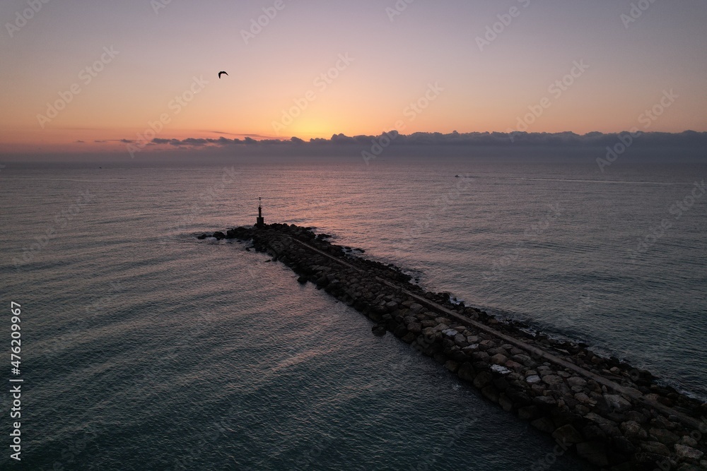 Amazing sunrise drone view over the Mediterranean Sea with a diagonal breakwater