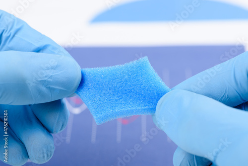 Blue porous foam material stretched in scientist hands in laboratory. Research for material with new properties concept. photo