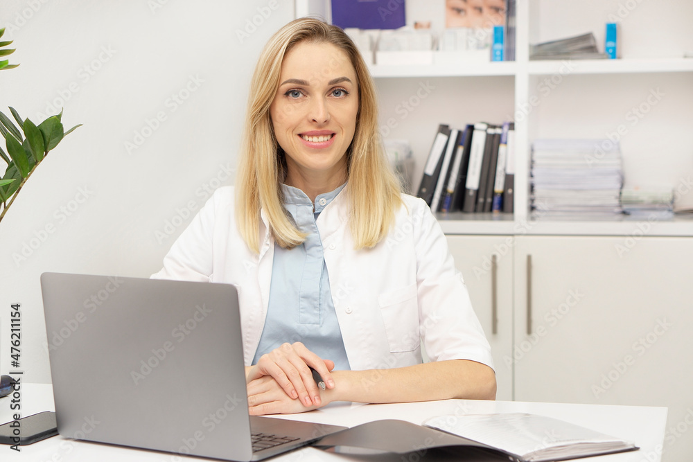 Female doctor working at office desk and smiling at camera, office interior on background. Medical healthcare and doctor staff service. Female doctor working at office desk and smiling at camera, office interior on background. Medical healthcare and doctor staff service.
