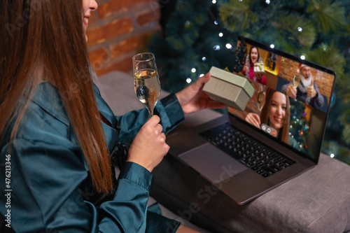 Side view of young girl using laptop, talking with friends, family by means of video calling. Christmas home decorations.