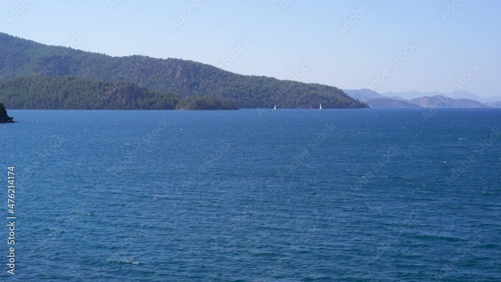 Beautiful summer marine landscape. Blue sea water, hills of mountains, sailing white yachts on horizon line