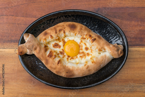 Wallpaper Mural Traditional Georgian cuisine. Ajara khachapuri with egg on black plate on wooden background Top view, close up with copy space. High quality photo Torontodigital.ca